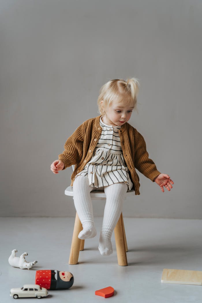 Adorable child sitting on a stool with toys, showcasing playful innocence.