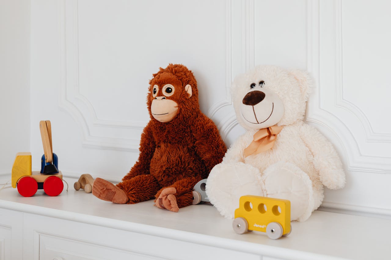 Home Cute plush teddy and monkey toys with wooden cars on a white shelf, perfect for kids' room decor.