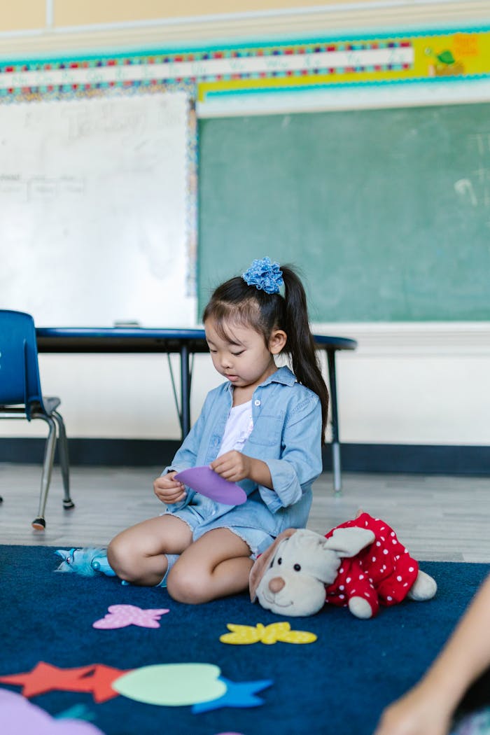 Young girl in a classroom setting, engaging with colorful paper toys, emphasizing early childhood education and creativity.